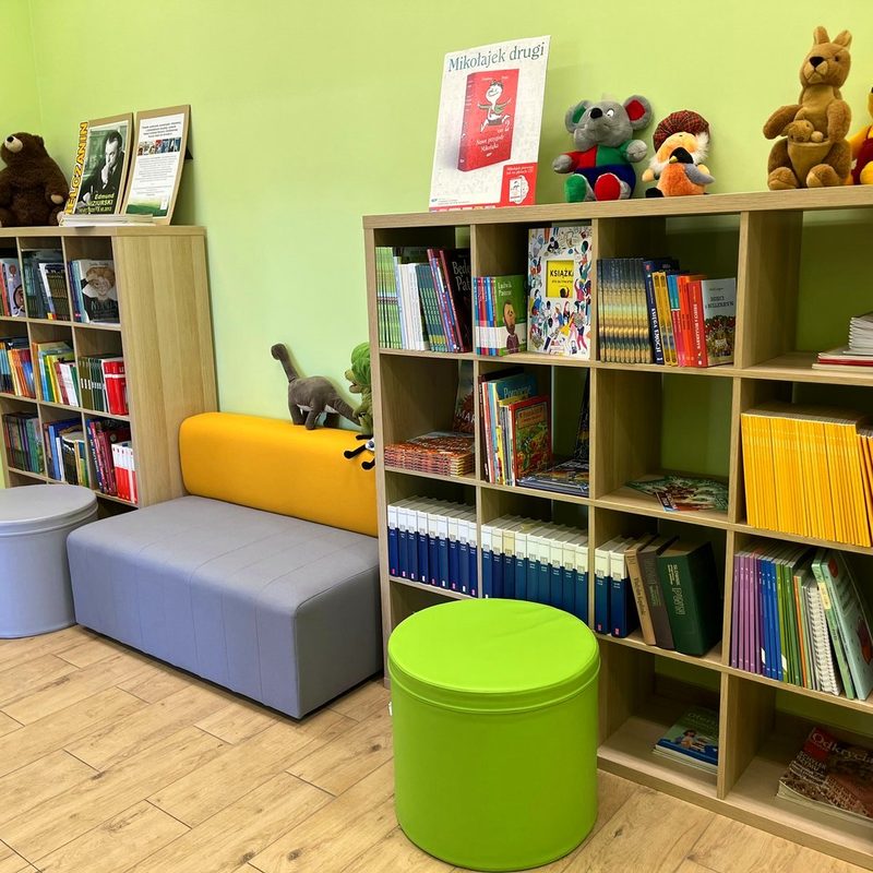 Kącik czytelniczy z regałami książek, pufami i miękką sofą