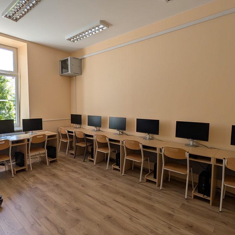 Pracownia komputerowa z rzędem stanowisk z monitorami i monitorem interaktywnym
