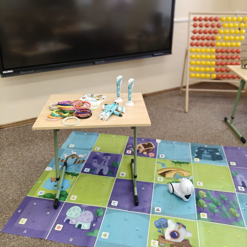 Robot edukacyjny Photon na macie do kodowania oraz długopisy 3D na stoliku